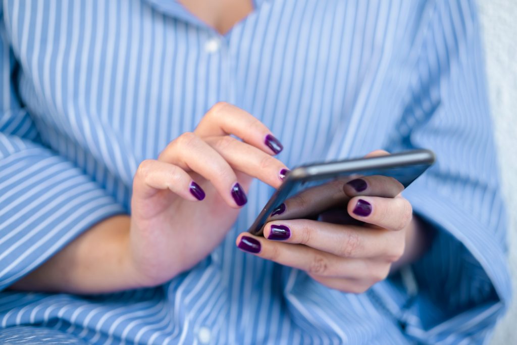Woman using mobile phone typing text, checking social media or shopping online.